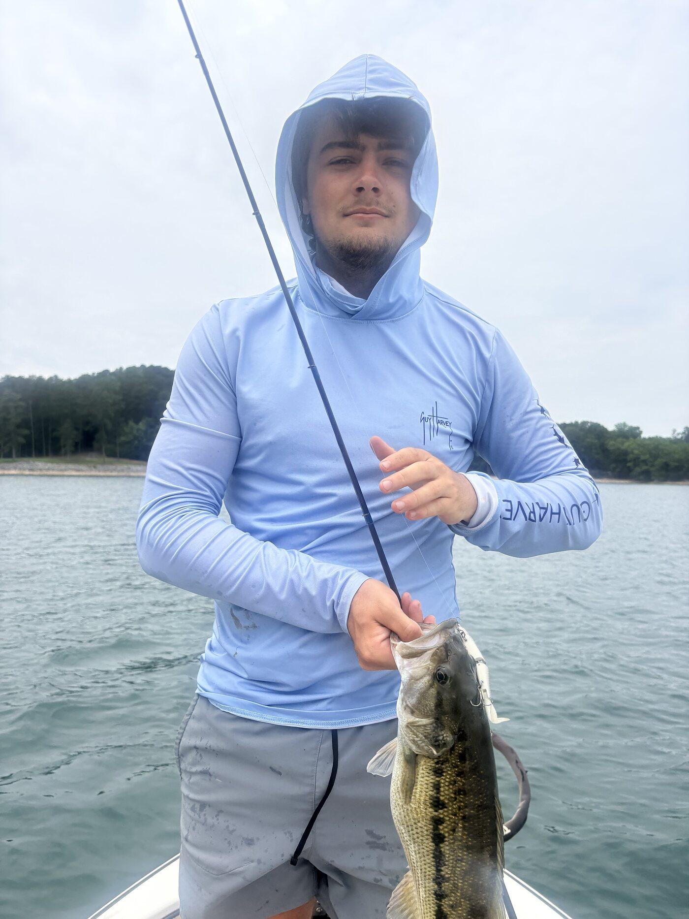 Angler on the lake with a rod, holding a bass